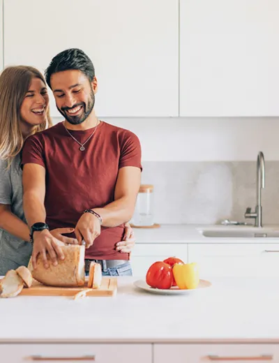 jeune couple souriant dans la cuisine liant couper du pain - mode de vie familial